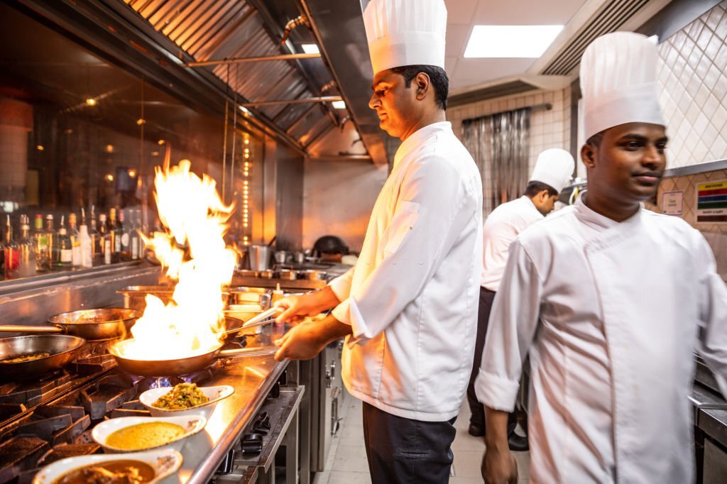 Indian chefs cooking in a professional kitchen of a gourmet restaurant.